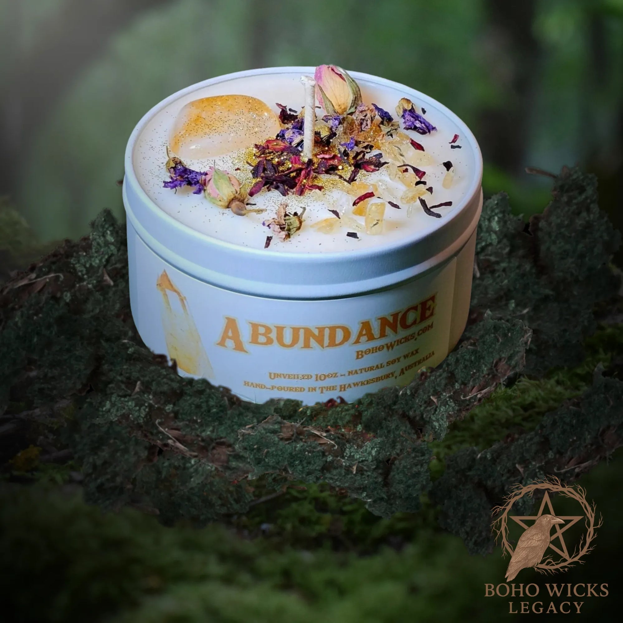 Forest setting photo of the Empowered Abundance candle with Citrine, Rose, Mallow, and Hibiscus surrounded by moss, fragranced with notes of Lavender, Grapefruit, Patchouli, Amber, and Sandalwood