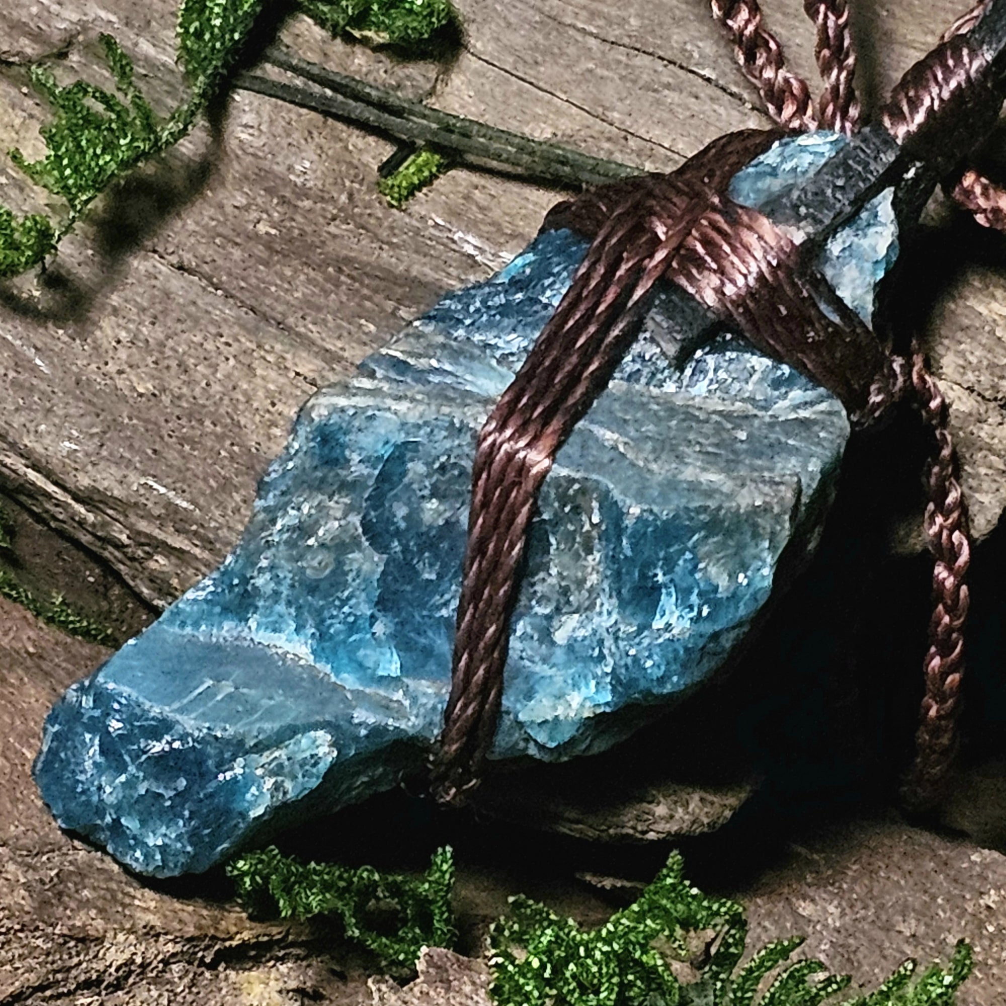 Apatite talisman necklace laid on bark and moss