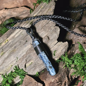 Natural kyanite crystal with woven thread, styled on log surface