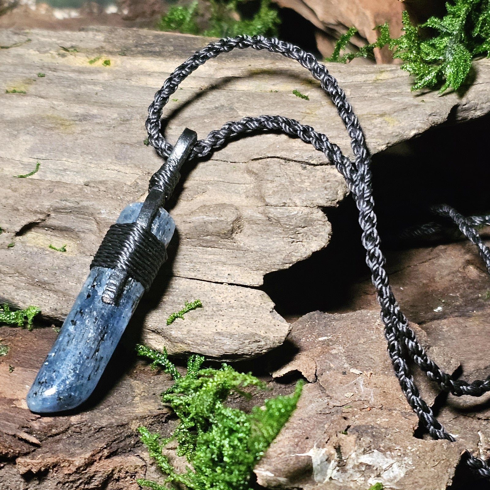 Kyanite crystal with dark inclusions resting on aged wood