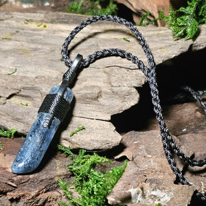 Kyanite crystal with dark inclusions resting on aged wood