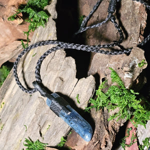 Deep blue kyanite necklace styled on wood and green moss