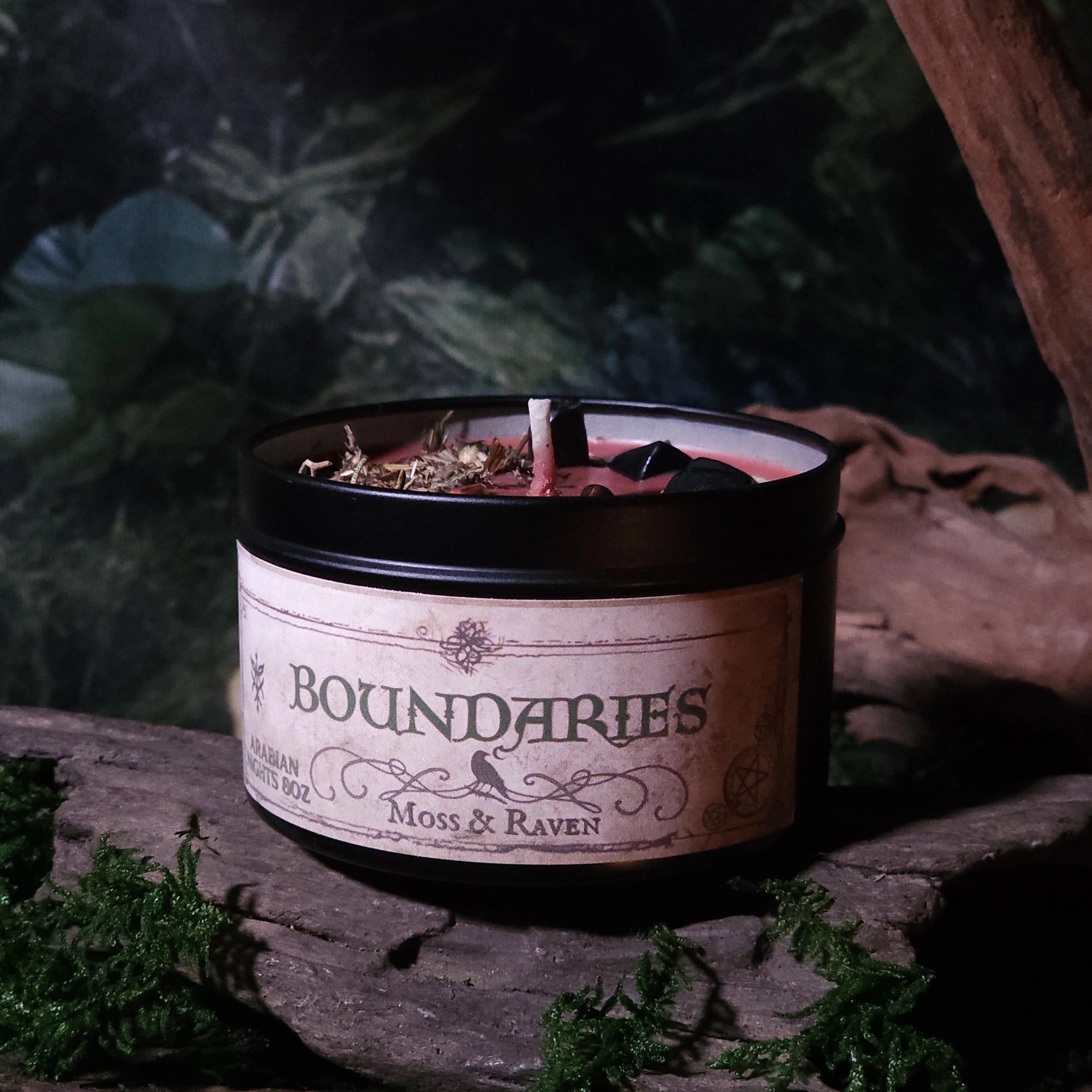 Candle labeled 'Boundaries' by Moss & Raven on a rustic wooden surface with a natural background.