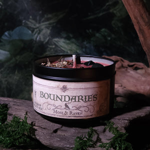 Candle labeled 'Boundaries' by Moss & Raven on a rustic wooden surface with a natural background.
