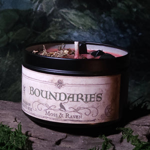 Candle with 'Boundaries' label by Moss & Raven on a dark background