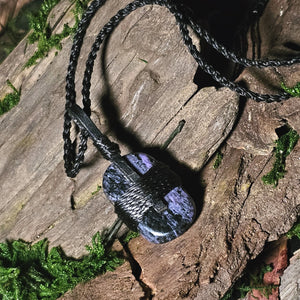 Polished charoite stone laid on wood and moss background