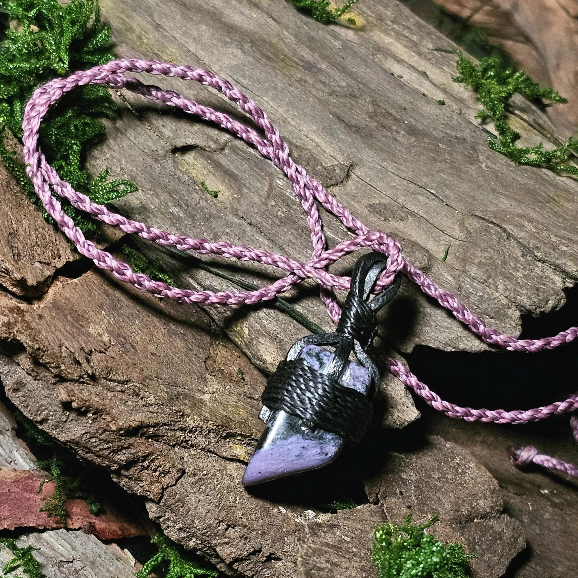 Side view polished charoite stone laid on wood and moss background