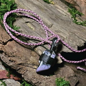 Side view polished charoite stone laid on wood and moss background