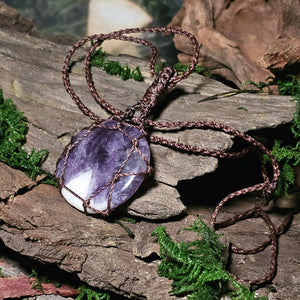 Amethyst talisman necklace laid on bark with moss