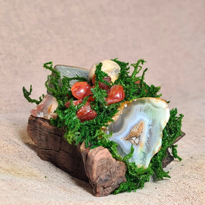 Close-up of flower agate and carnelian crystals set in moss and driftwood sculpture.