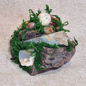 Pagan altar decor with moss, driftwood, and vibrant red-orange carnelian stones.