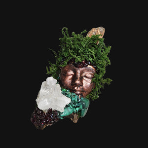 Handcrafted Forest Guardian sculpture featuring a copper-bronze face framed with preserved moss, Malachite, Garnet, and a Clear Quartz cluster on driftwood.