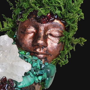 Close-up of a Forest Guardian by Moss & Raven — moss-crowned copper face with Malachite, Garnet, and Clear Quartz crystals nestled in driftwood.