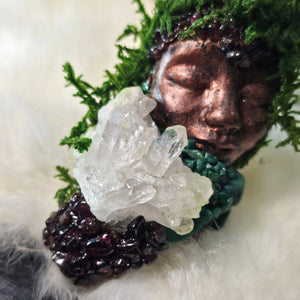 One of a kind moss guardian resting on driftwood with crystal details, close up