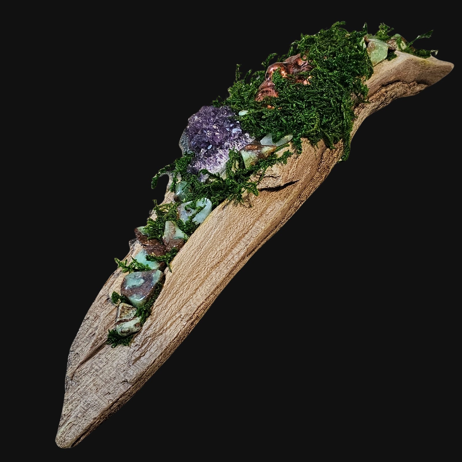Angled view of Forest Guardian: The Verdant King — handcrafted driftwood sculpture featuring a copper masculine face surrounded by moss, Amethyst cluster, and Chrysoprase stones symbolising growth and strength.