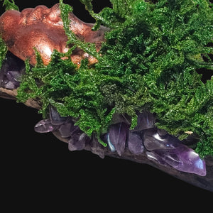 Close-up of copper-bronze Forest Guardian face framed by moss and crystals — symbol of peace and spiritual awareness.