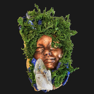 Close-up of a handcrafted Forest Guardian sculpture with moss, copper-bronze face, and Lapis Lazuli stones surrounding a Clear Quartz point, by Moss & Raven.
