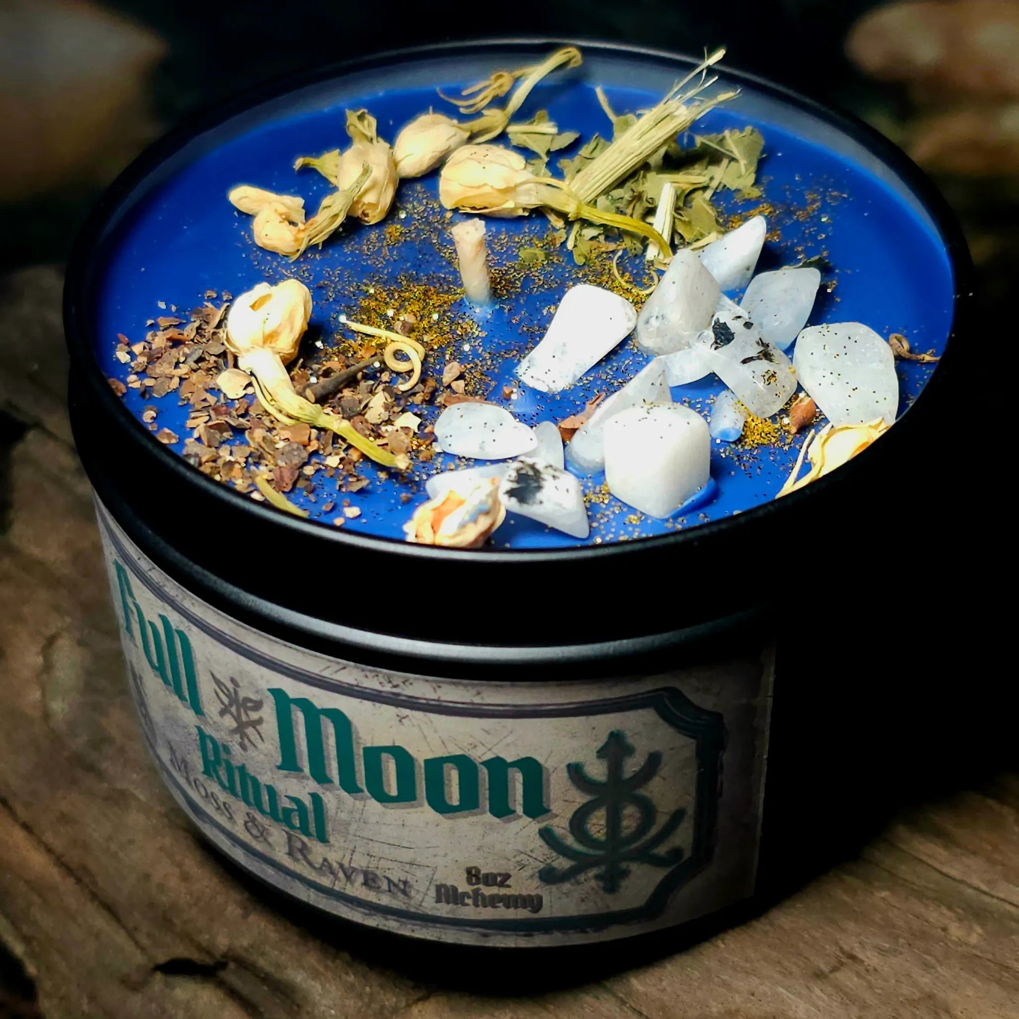 Full Moon Ritual Candle close-up – deep blue wax with moonstone crystals, jasmine buds, herbs, and golden shimmer for lunar ritual