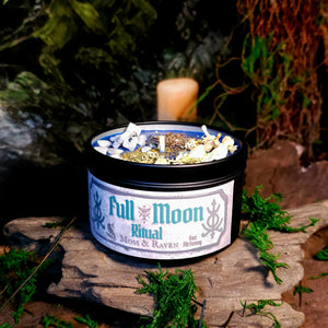 Full Moon Ritual Candle on altar setting – blue wax candle with moonstone, jasmine, and herbs in black tin marked Full Moon Ritual