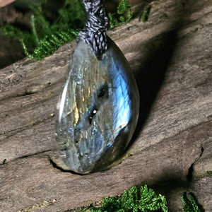 Artisan pendant laid on natural wood with labradorite shimmer