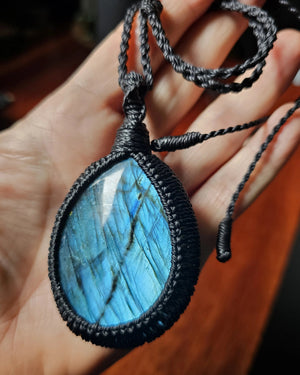 Ritual Labradorite talisman photographed in hand showing natural blue flash with black cord