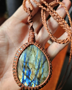 Ritual Labradorite talisman photographed in hand showing natural blue flash with copper cord