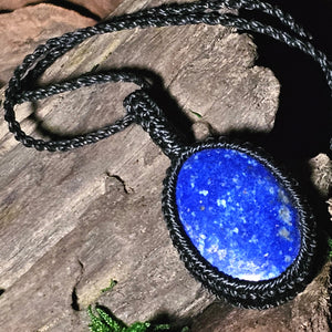 Lapis lazuli stone pendant laid on rustic wood and moss