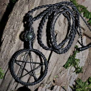 Black pentacle talisman necklace with moss agate bead resting on natural bark