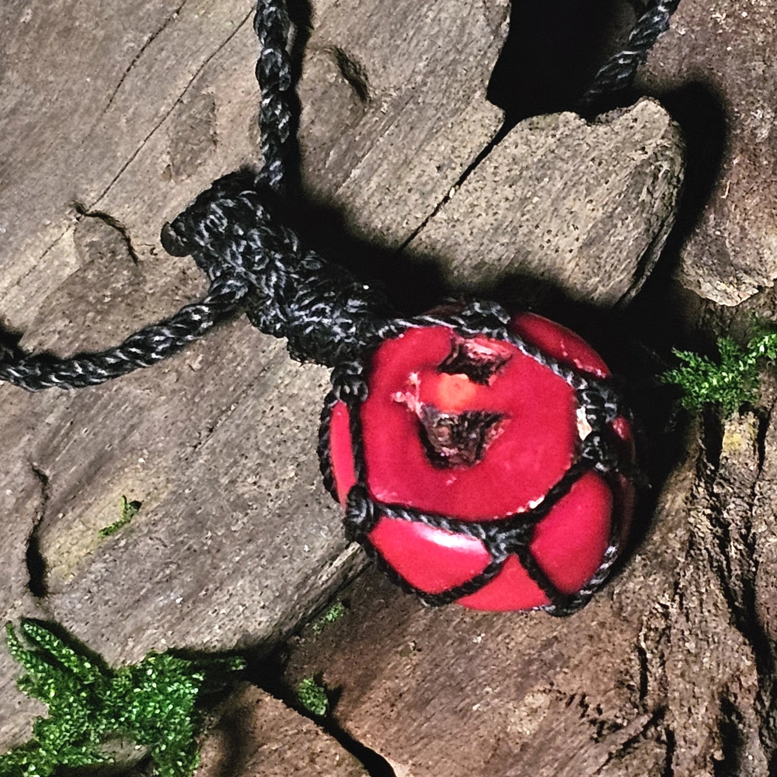Red coral pendant wrapped in black woven cord