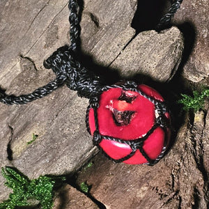 Red coral pendant wrapped in black woven cord