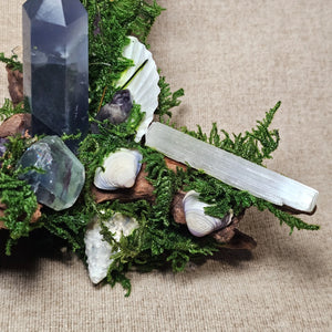 Detail of Selenite wand channeling light through moss and crystal arrangement.
