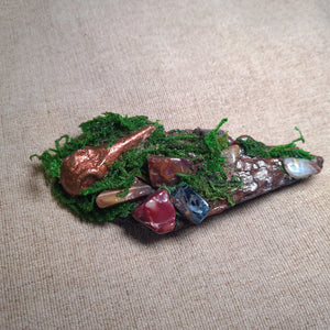 Witch-crafted driftwood altar with moss and copper raven figure resting among earthy crystals – The Raven’s Nook.