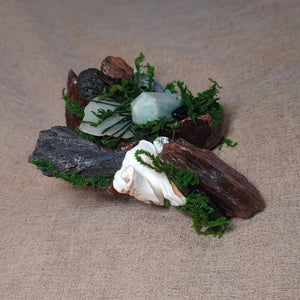 Amazonite point beside black protective stones on weathered wood.