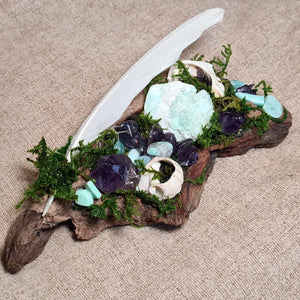 Magical altar piece with white feather, green moss, and soothing ocean-hued crystals – Moss & Raven.