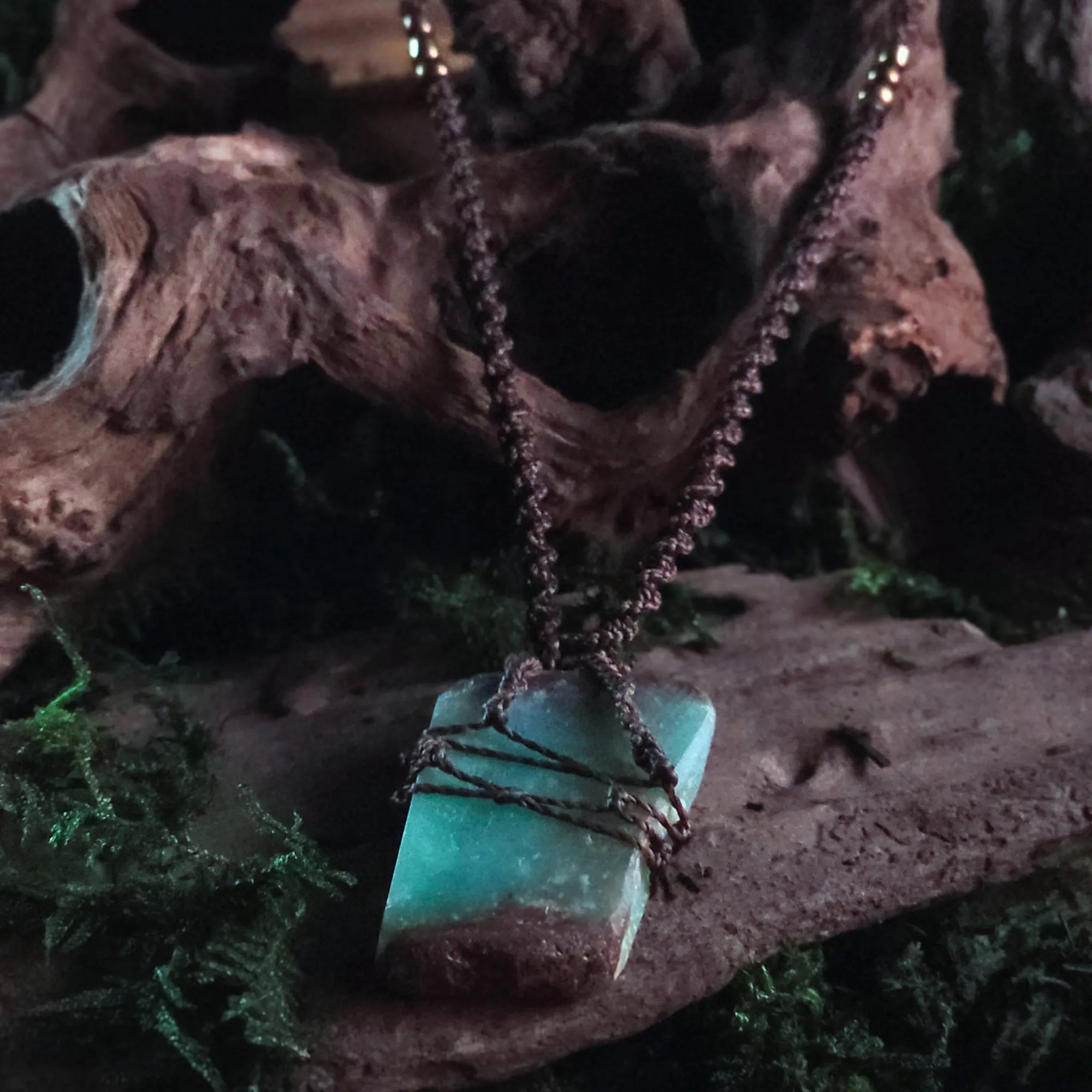 Chrysoprase talisman displayed outdoors on driftwood with moss and ritual elements – spiritual necklace design

