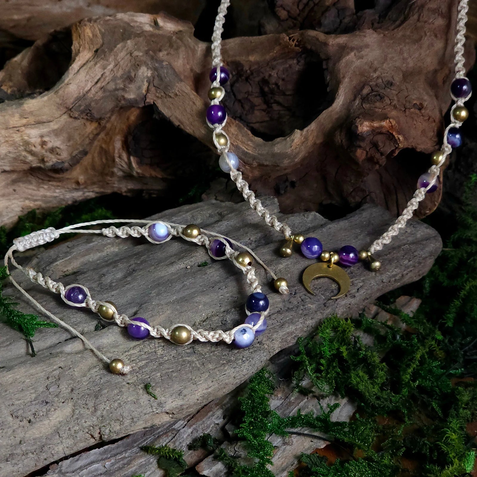 Natural cord necklace and bracelet set with chevron amethyst and blue lace agate beads, brass accents, and a brass crescent moon pendant, styled on driftwood and moss.