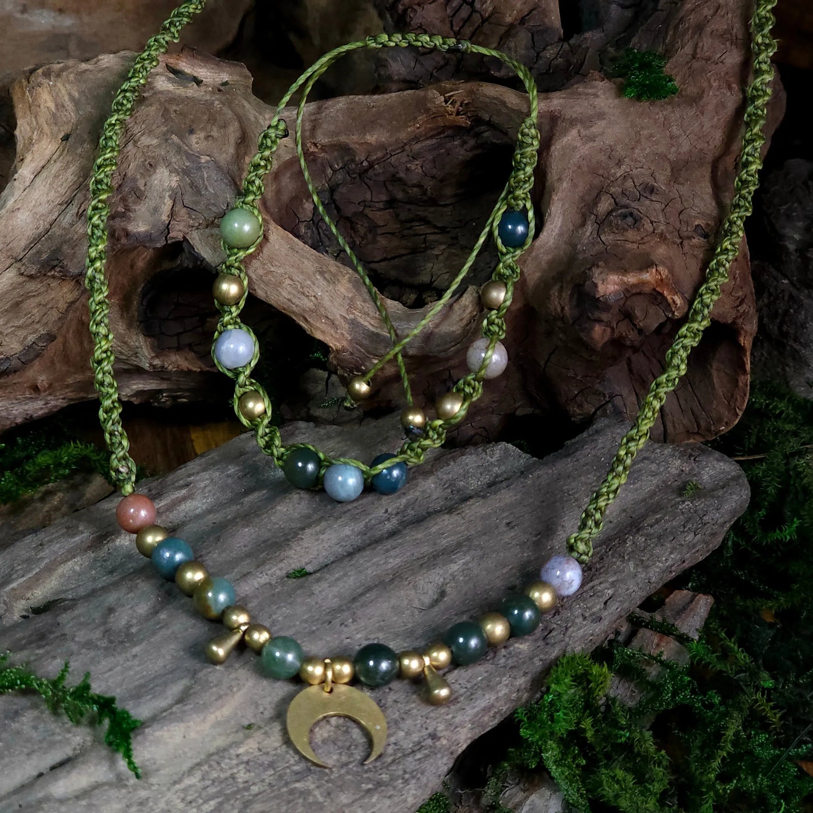 Green cord necklace and bracelet set featuring ocean jasper beads, brass accents, and a brass crescent moon pendant, styled on driftwood with moss.