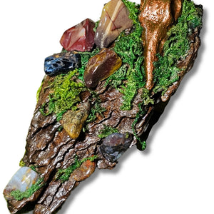 The Raven’s Nook miniature crystal forest by Moss & Raven on white background. Features Pietersite, Mookaite, moss, driftwood, and a sculpted raven head.