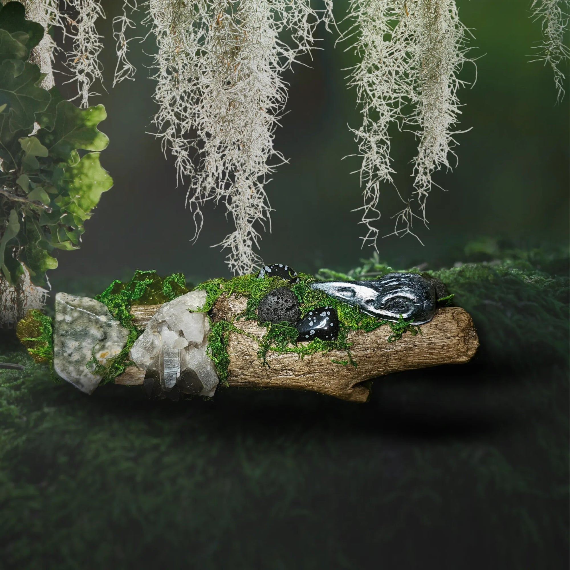 Watcher of the Veil crystal forest by Moss & Raven shown on moss and stone. Features Smokey Quartz cluster, Snowflake Obsidian, Lava Stone, Ocean Jasper slab, moss, driftwood, and a hand-sculpted raven’s head.