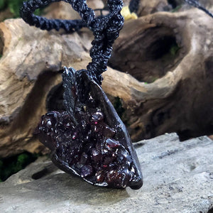Side angle showing the layered texture of black kyanite and hand-placed garnet on rustic wood.