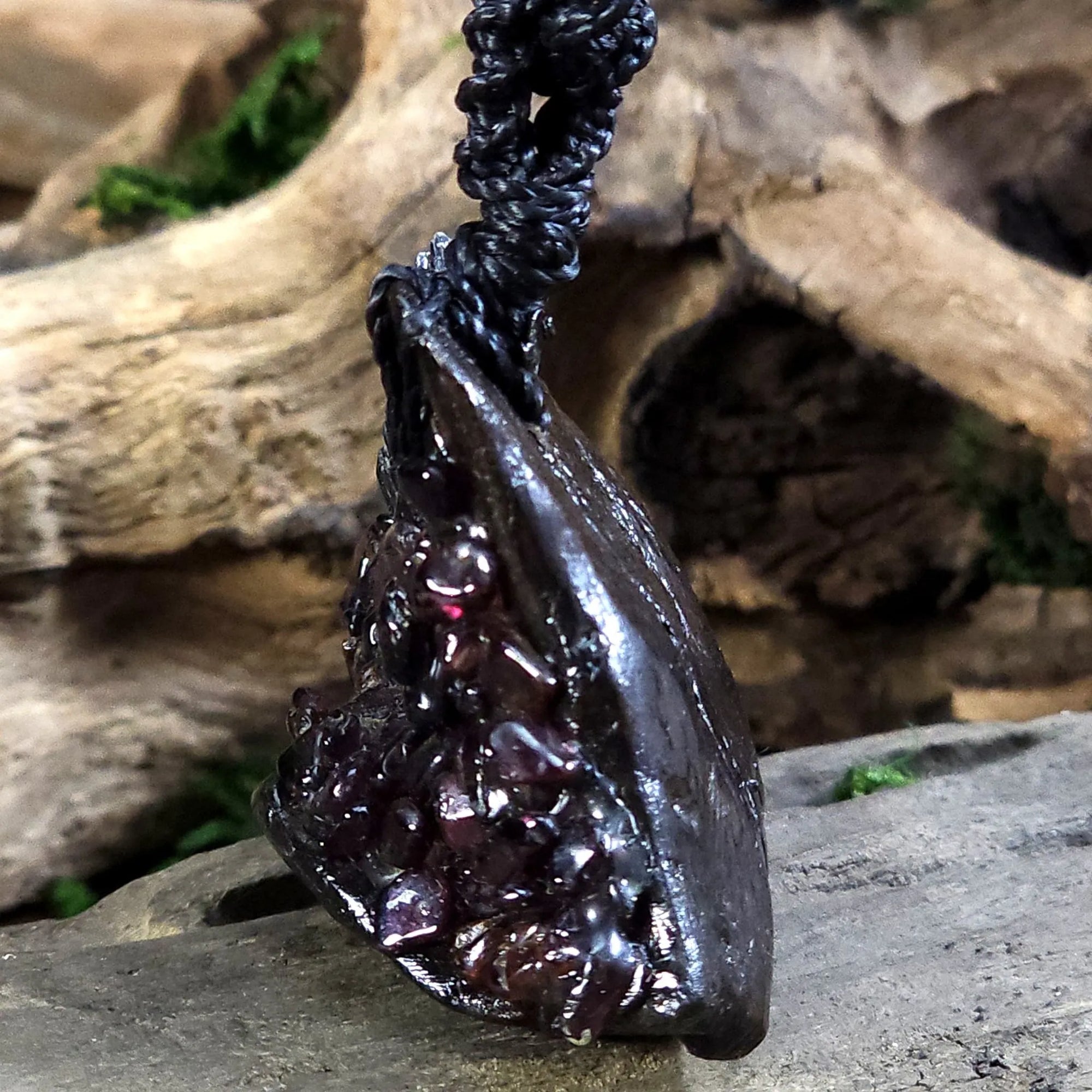 Side angle showing the layered texture of black kyanite and hand-placed garnet on rustic wood.