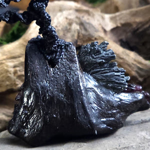 Rear view of the Witch Queen’s Shield Talisman showing the raw driftwood backing, black cord attachment, and natural placement of kyanite and garnet from behind.
