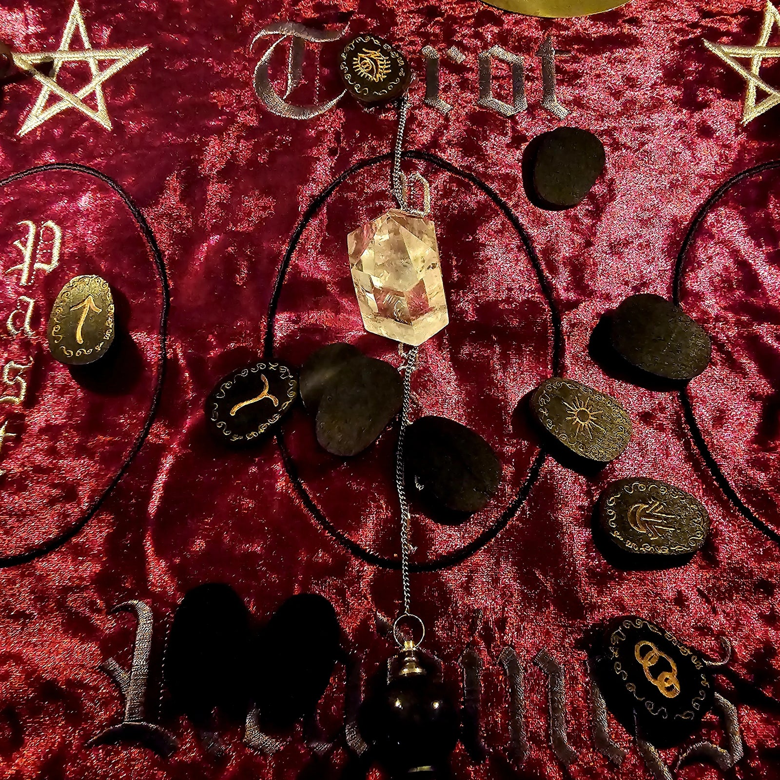 Witch's Rune set on red velvet reading cloth with crystal pendulum and casting layout