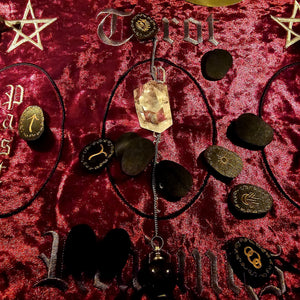 Witch's Rune set on red velvet reading cloth with crystal pendulum and casting layout